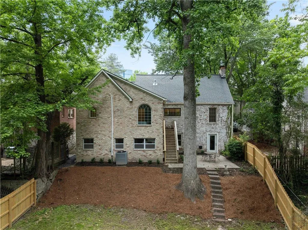 Back of house featuring a patio area, stairway, a fenced backyard, brick siding, and a chimney