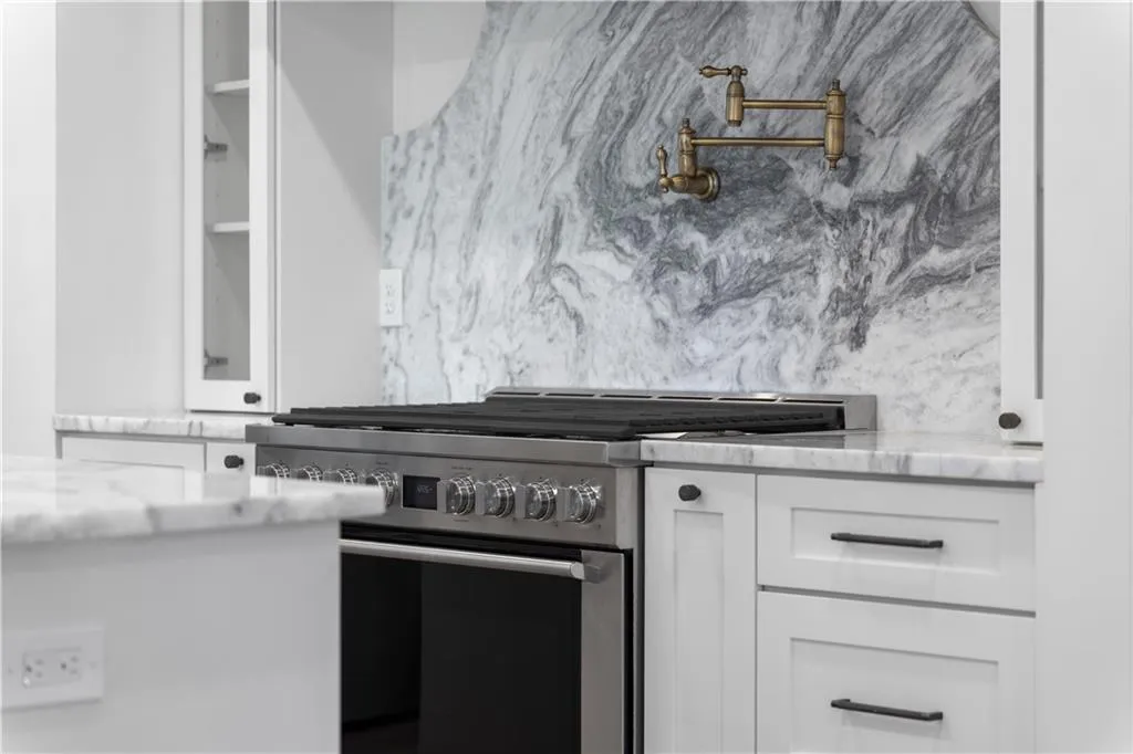 Kitchen featuring high end stove, white cabinets, and light stone countertops