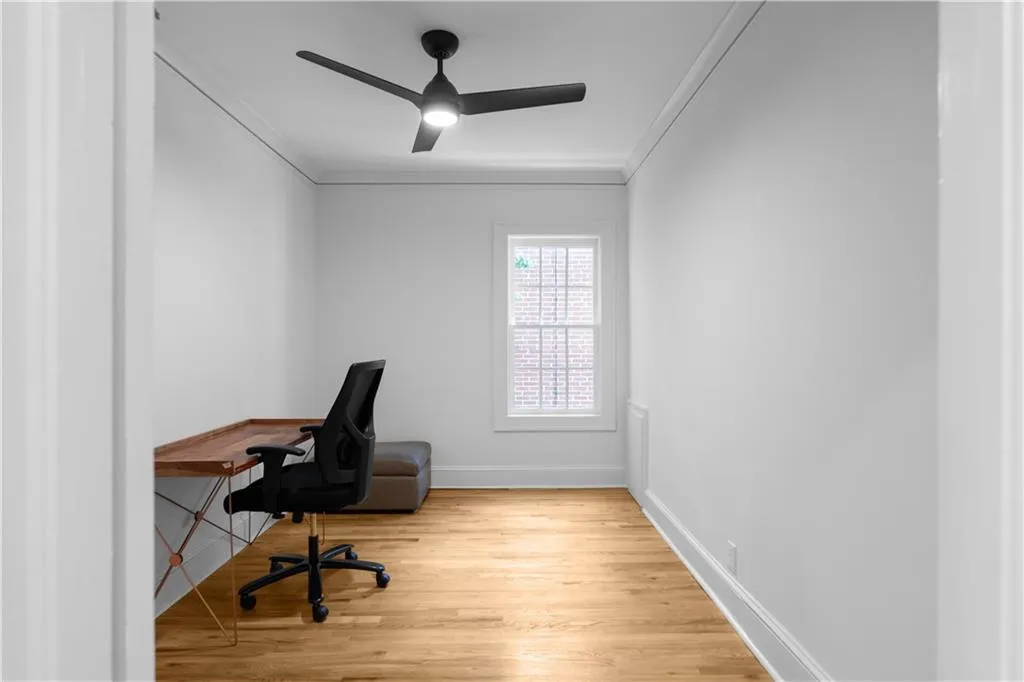 Office space featuring ceiling fan, ornamental molding, wood finished floors, and baseboards