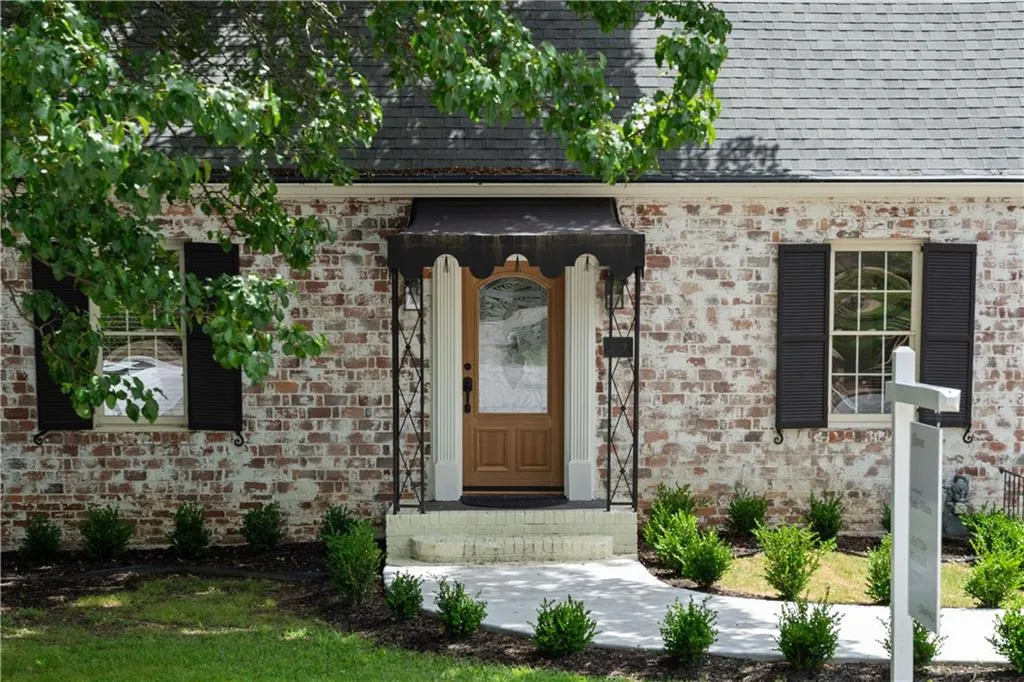 Property entrance with a shingled roof and brick siding