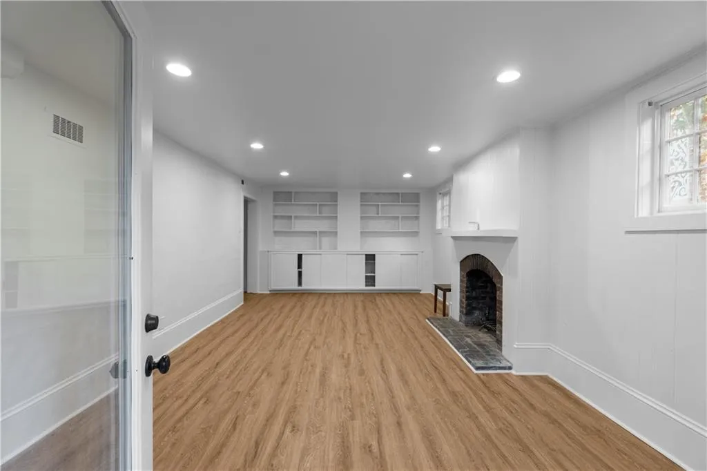 Unfurnished living room featuring a fireplace, light wood-type flooring, recessed lighting, baseboards, and built in features