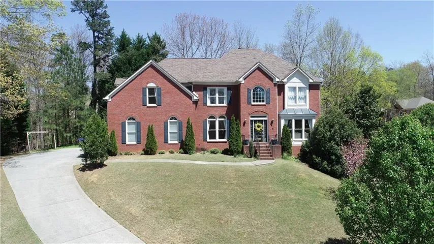 Brick exterior, arched windows, bay window, gabled roof, and a paved driveway