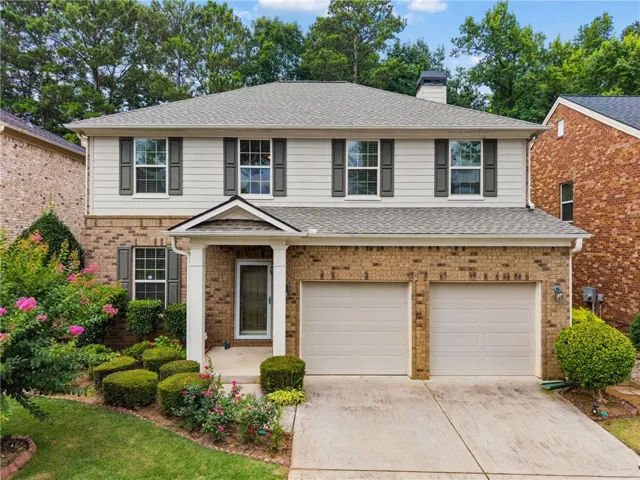 Two-story home featuring a brick and siding exterior, a two-car garage, and a covered front entry