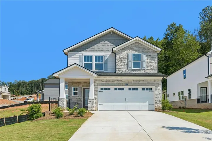 Two-story exterior with stone and siding accents, prominent front entry porch, attached two-car garage, concrete driveway, and manicured front lawn