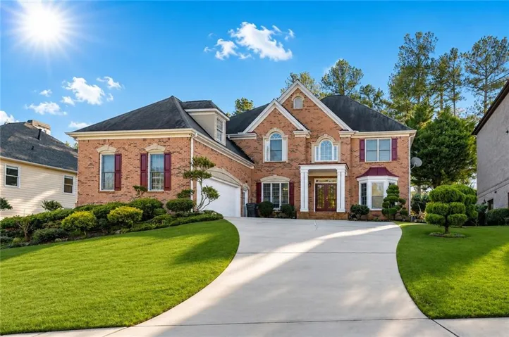 Brick facade residence featuring a prominent portico entrance with double doors, arched windows, and a bay window
