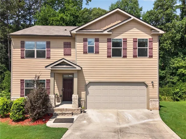 Two-story residence featuring light-colored siding with contrasting shutters, a covered porch entrance, an attached garage, and a concrete driveway
