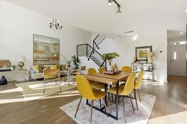 Open-concept living area with wood-finish flooring, high ceilings, and a contemporary chandelier