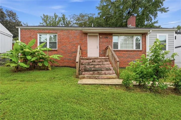 Brick facade with an offset entry, front porch with wood railings, and a prominent chimney