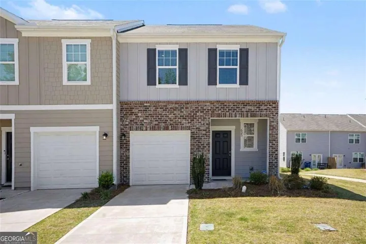 Brick and siding exterior with a covered porch, white-trimmed windows, dark shutters, and an attached garage