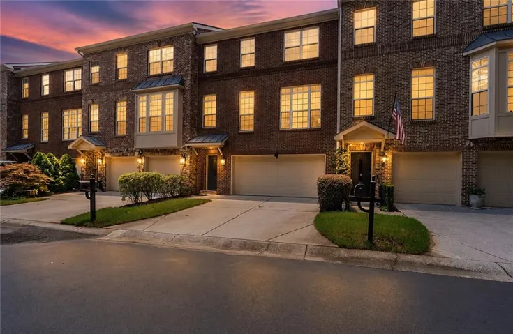 Brick exterior architecture with multiple window configurations, individual garage access, and covered entryways
