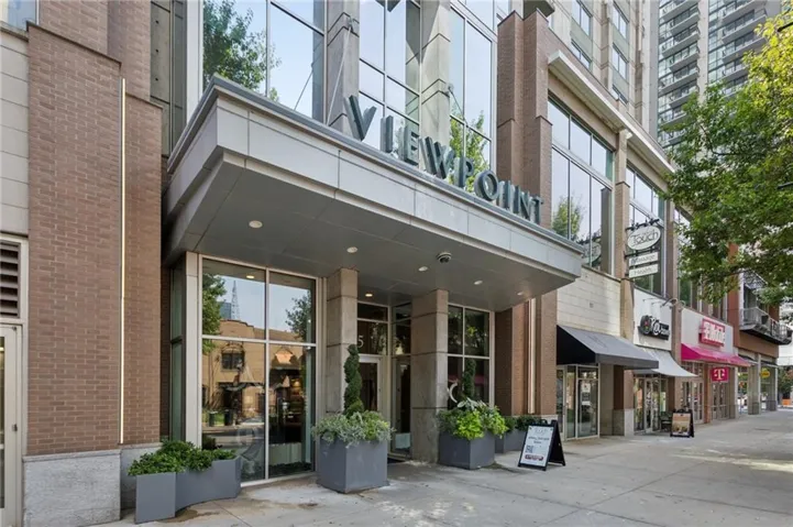 Modern building facade with a prominent entrance canopy, large storefront windows, and brick detailing