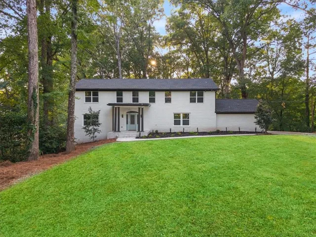 Two-story residence featuring a white brick exterior, dark roof, and a covered portico entrance