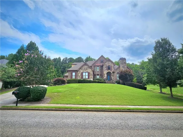 Stone and brick facade residence with a prominent front entrance, arched doorway, and dark shutters