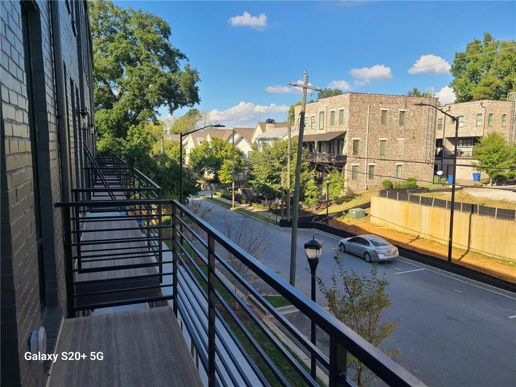 Balcony with black metal railings and wood-finish flooring, featuring exterior wall lighting