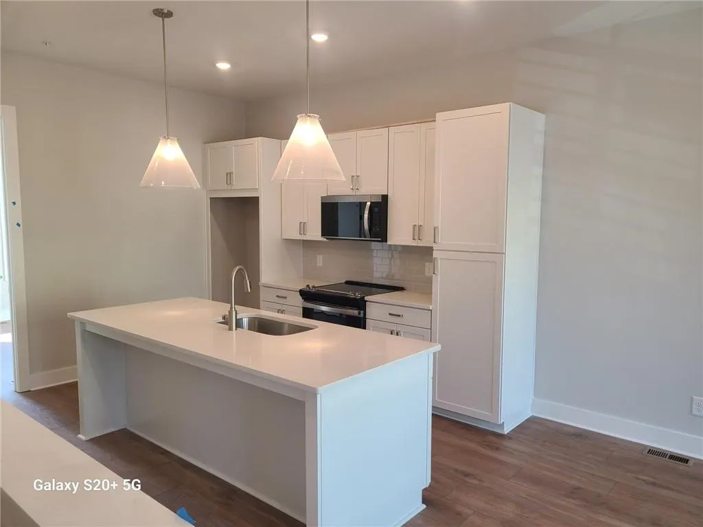 White shaker cabinetry, recessed lighting, and wood-finish flooring