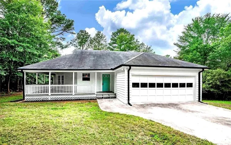 Ranch-style residence featuring white siding, a covered front porch with white railings, and a prominent two-car garage with a panel door