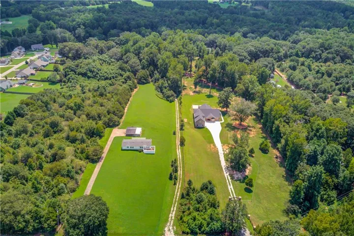 Expansive green acreage featuring two distinct residential structures and mature tree lines
