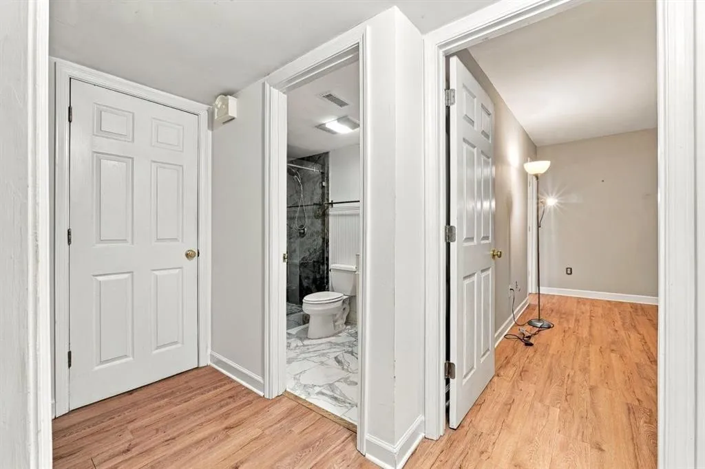 Wood-finish flooring throughout, white paneled doors with brass hardware, and light gray walls