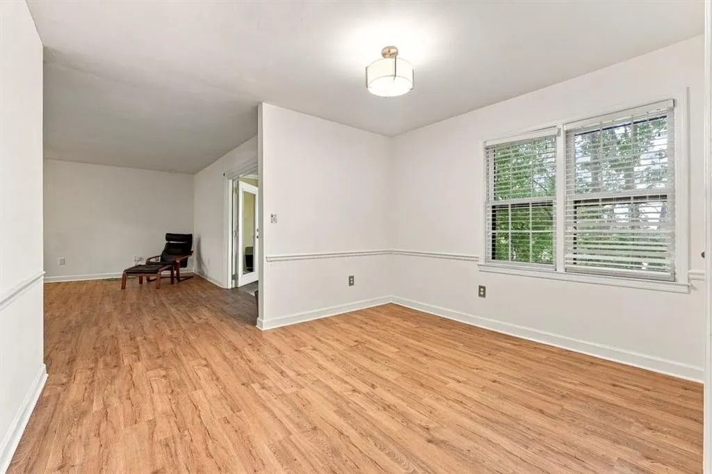Wood-finish flooring, white walls with chair rail molding, two large windows, and a flush-mount ceiling light fixture
