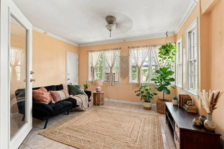 Tile flooring, multiple large windows, ceiling-mounted light fixture, white crown molding, and a white interior door
Virtually staged photo