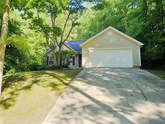 Single-story residence featuring light-colored siding, a prominent two-car garage, and a concrete driveway