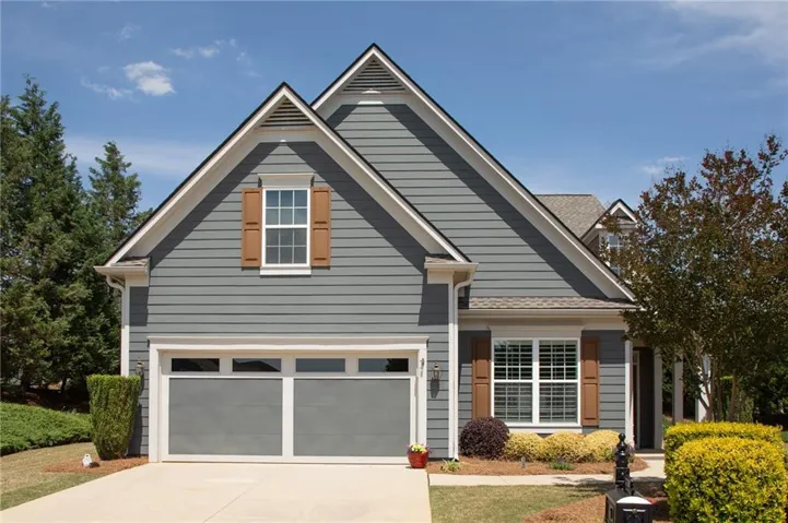 Exterior showcasing gray siding, white trim, wood-tone shutters, and a two-car garage with frosted windows