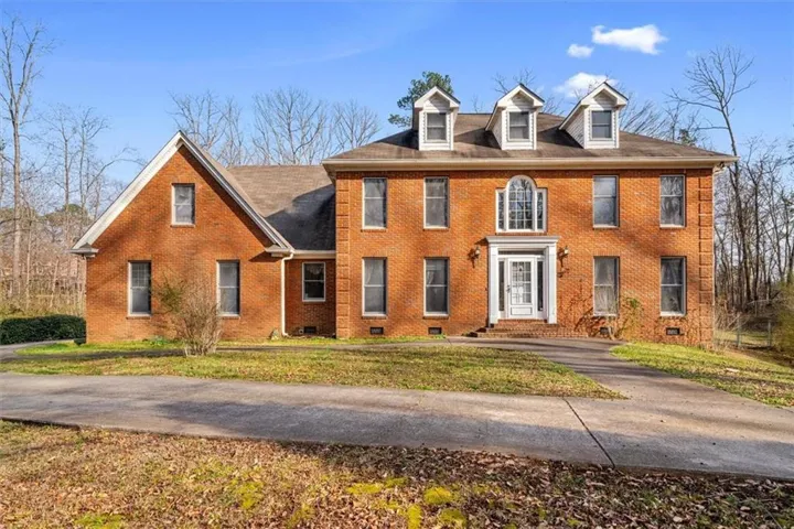 Brick exterior with multiple dormer windows, a prominent gable, and an arched transom above the entry