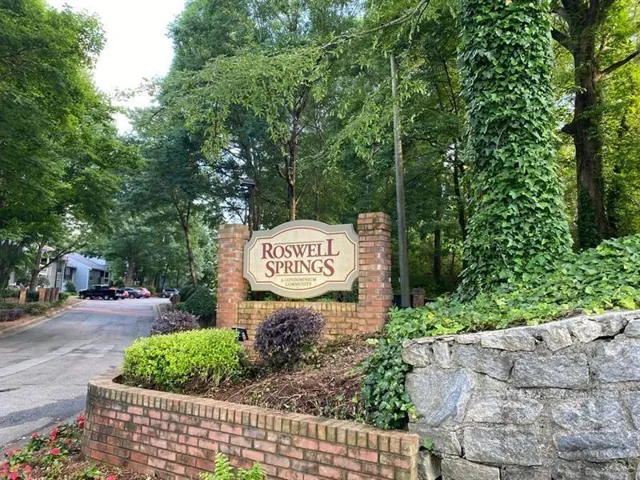 Roswell Springs community entrance featuring a brick and stone sign, mature trees, and established landscaping