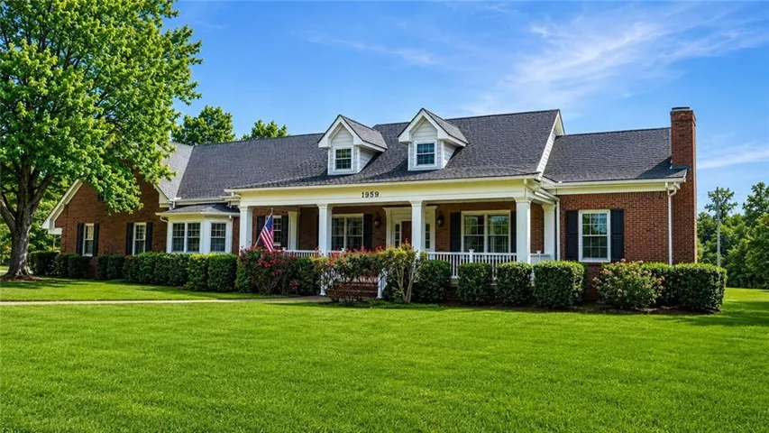 Brick exterior with black shutters and a covered front porch featuring white columns
