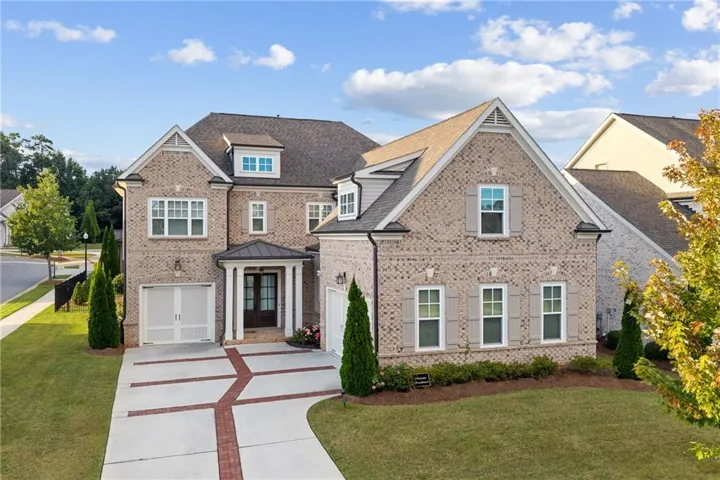 Brick Colonial estate with a covered entry portico, multi-pane windows, and a brick-and-concrete curved walkway