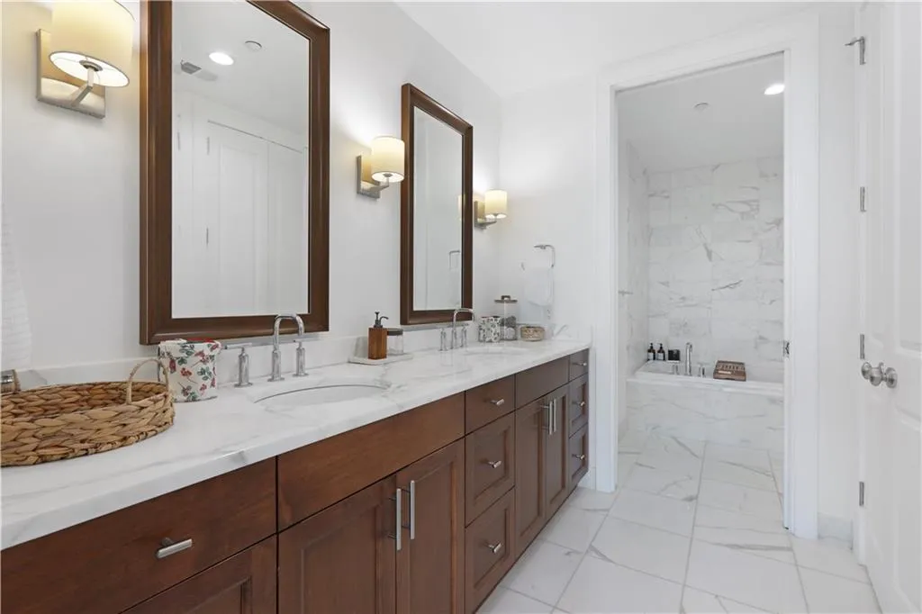 Full bath with double vanity, light marble finish floors, recessed lighting, and a soaking tub