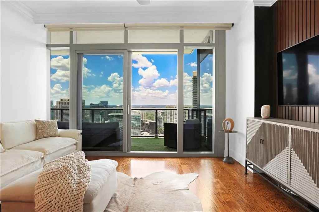 Living room with wood finished floors, expansive windows, crown molding, and a view of city