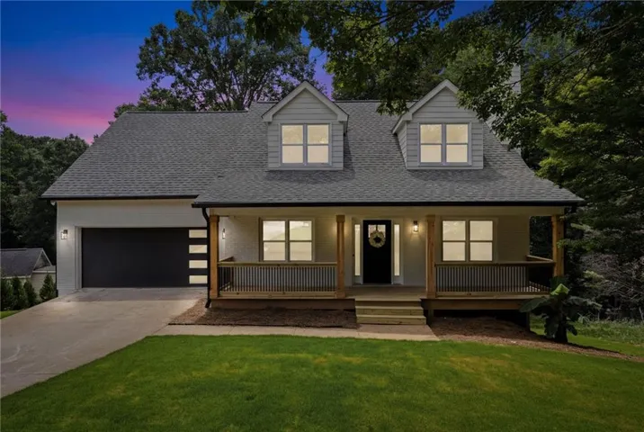 Contemporary Craftsman-style home featuring a covered front porch with wood columns, a modern black garage door with frosted glass panels, and dormer windows
