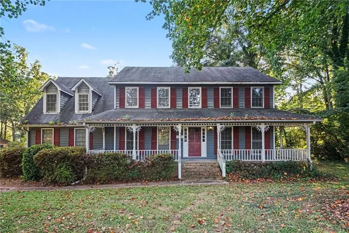 Traditional-style residence with a full-width covered porch, decorative porch railing, and dormer windows