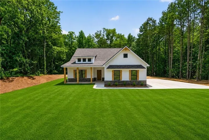 Single-story residence with white siding, dark roof, and a front porch supported by wood columns