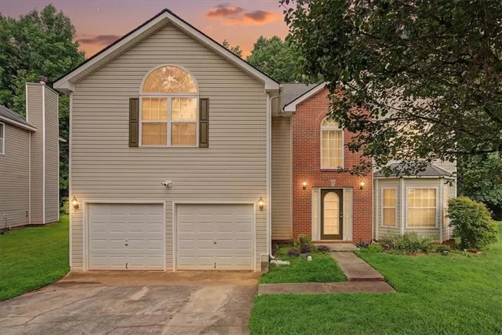 Two-car garage, partial brick facade, arched front door, bay window, and gabled roof