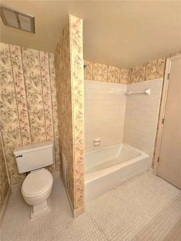Full bathroom featuring wallpapered walls,  shower combination, and tile patterned floors