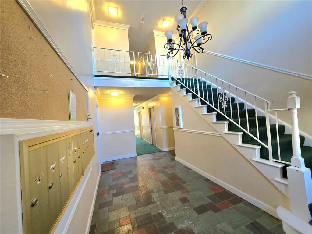 Stairs with crown molding, a chandelier, a high ceiling, and stone finish flooring