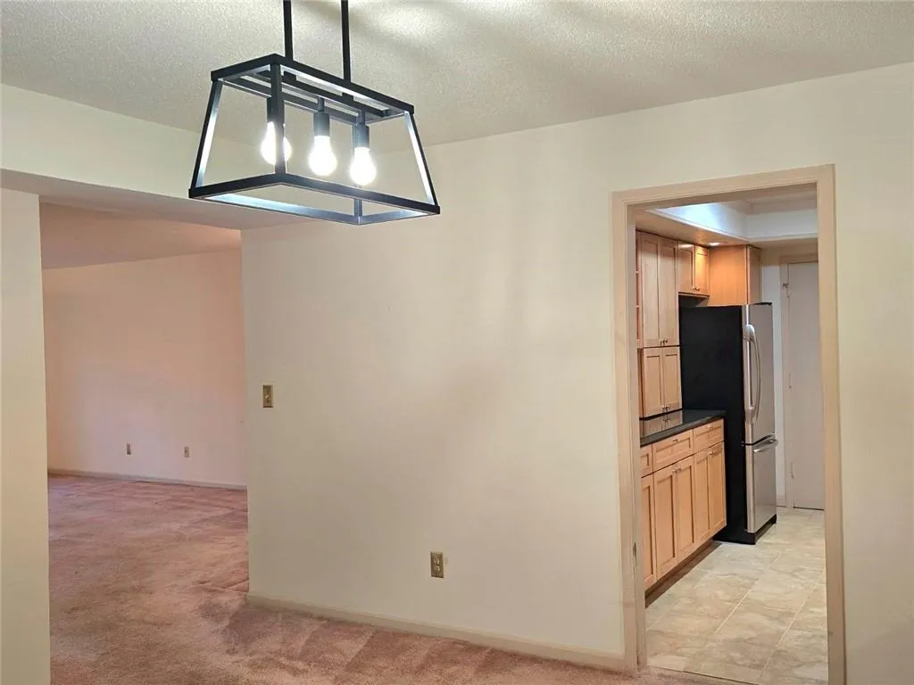 Unfurnished dining area featuring a textured ceiling and light colored carpet