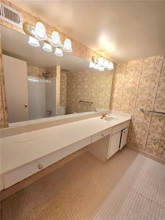 Full bathroom with vanity, a shower, and wallpapered walls