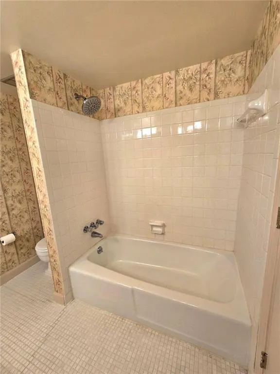 Bathroom featuring bathing tub / shower combination, wallpapered walls, and tile patterned flooring