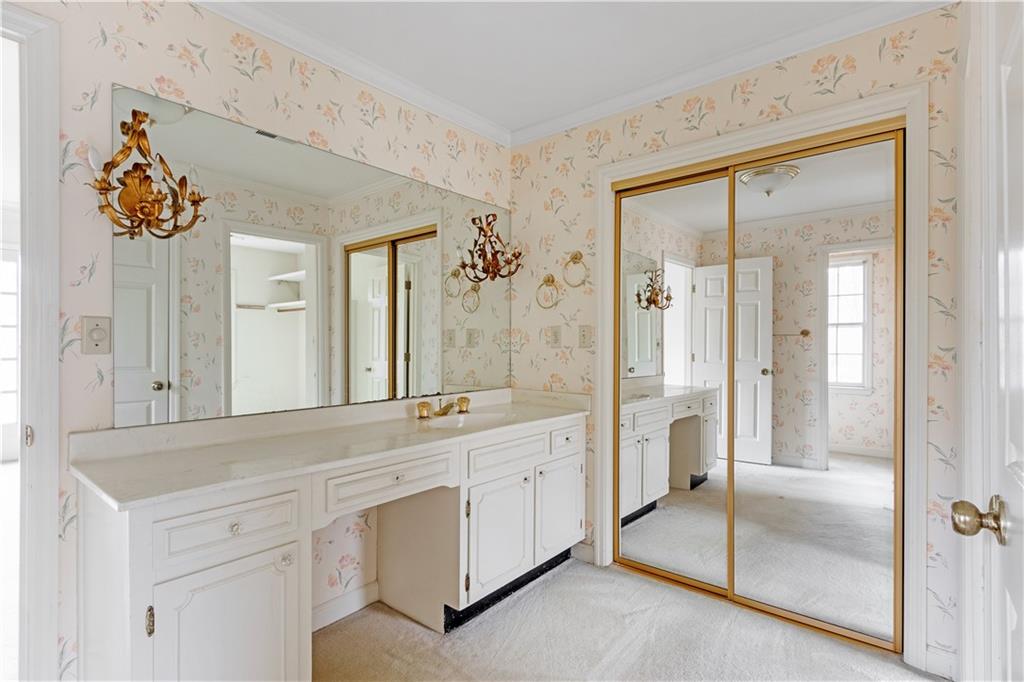 Bathroom featuring crown molding and vanity with extensive cabinet space, his and hers closets