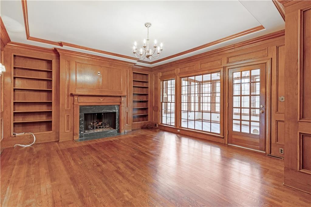 Study with a fireplace, a chandelier, built in shelves, ornamental molding, and hardwood flooring