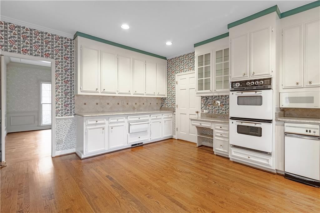 Kitchen featuring white cabinets, white appliances, and hardwood flooring