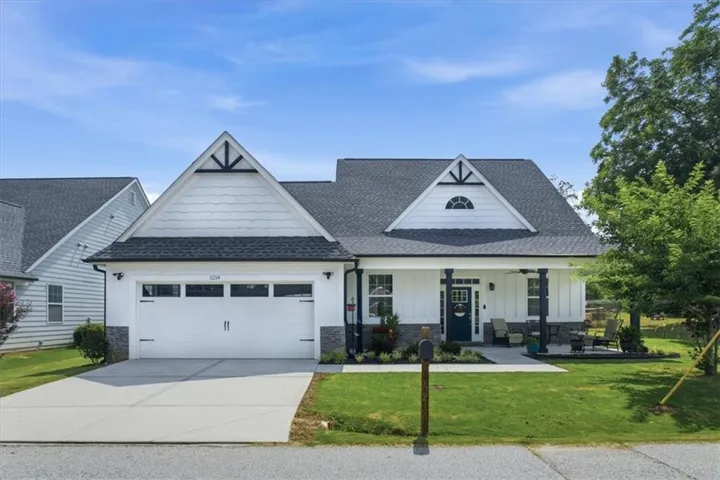 Single-story residence featuring a white board and batten facade, dark shingle roof, and stone veneer accents