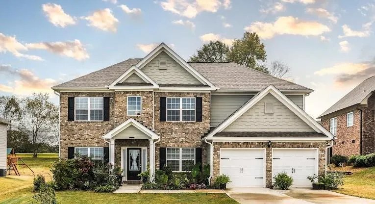 Two-story residence featuring a brick facade with complementary siding and shingle accents