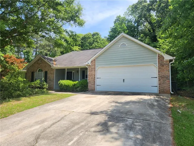 Brick and siding exterior with an attached two-car garage, covered entry, and mature landscaping