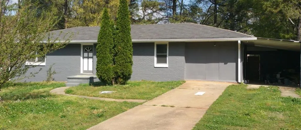 Gray exterior with white trim, featuring a paved driveway, front walkway, and covered carport