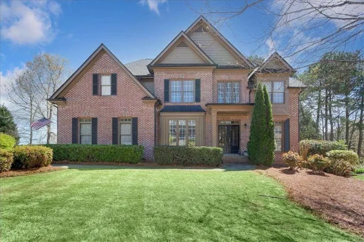 Brick exterior featuring dark shutters and a gabled roofline