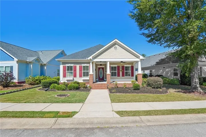 Craftsman-style home featuring a covered front porch with brick columns, red shutters, and a front entry door with an oval glass insert